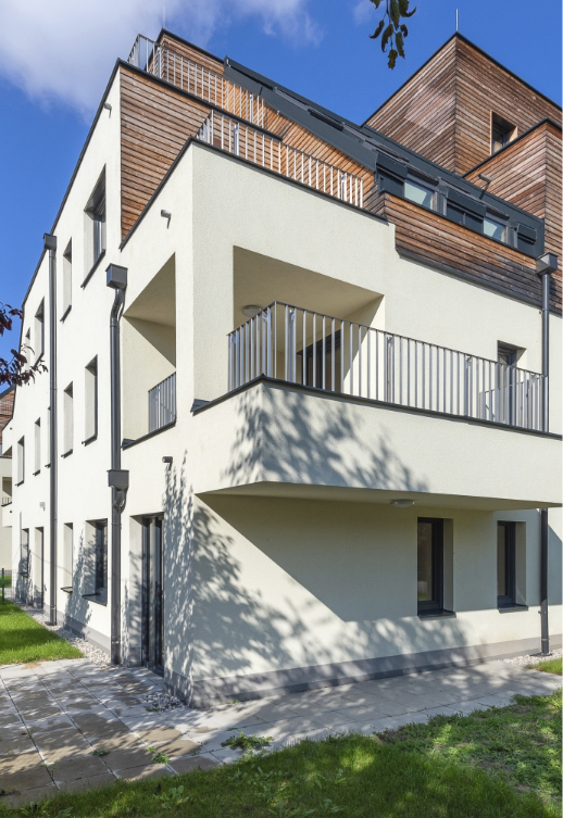 Modernes Wohngebäude mit weißer Fassade, Holzverkleidung und Balkonen.