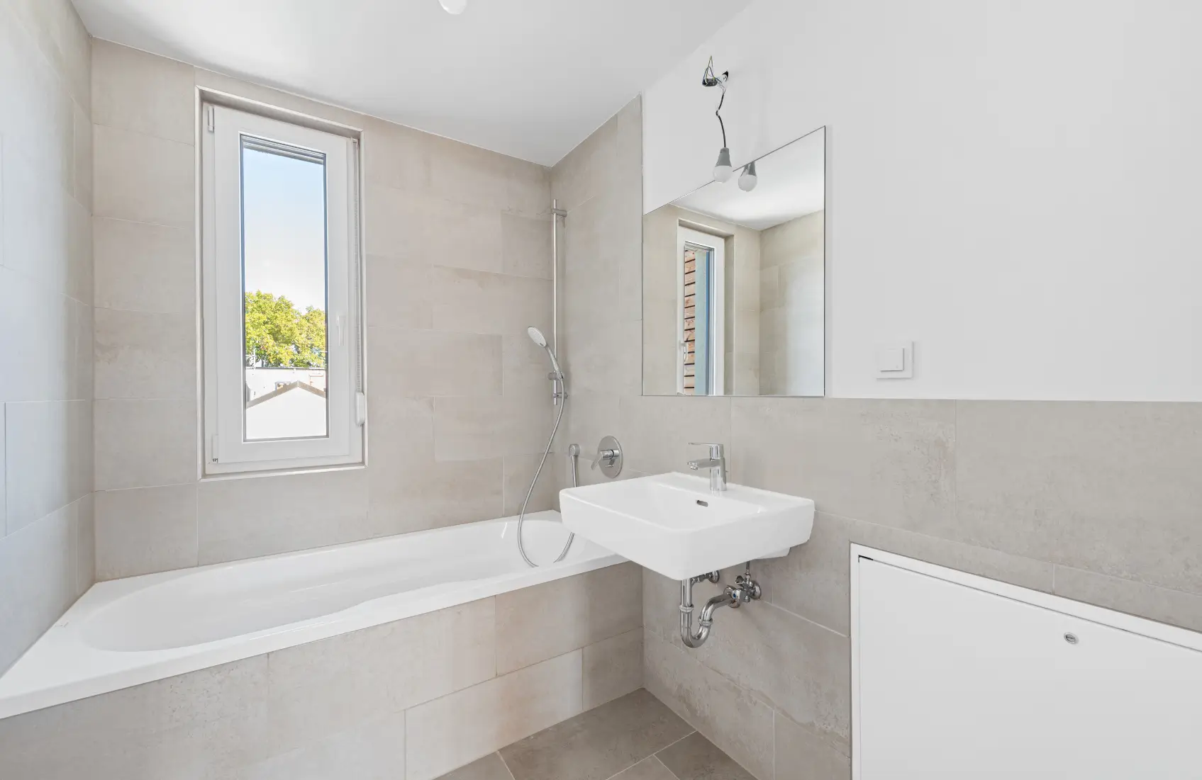 Modernes Badezimmer mit Badewanne, Waschbecken und hellem Fliesenspiegel.