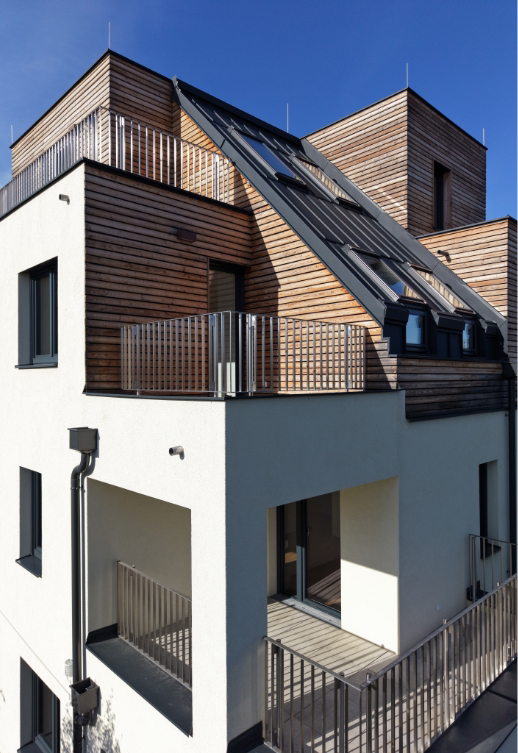 Ansicht eines modernen Wohnhauses mit weißem Putz und Holzverkleidung auf dem Dach.